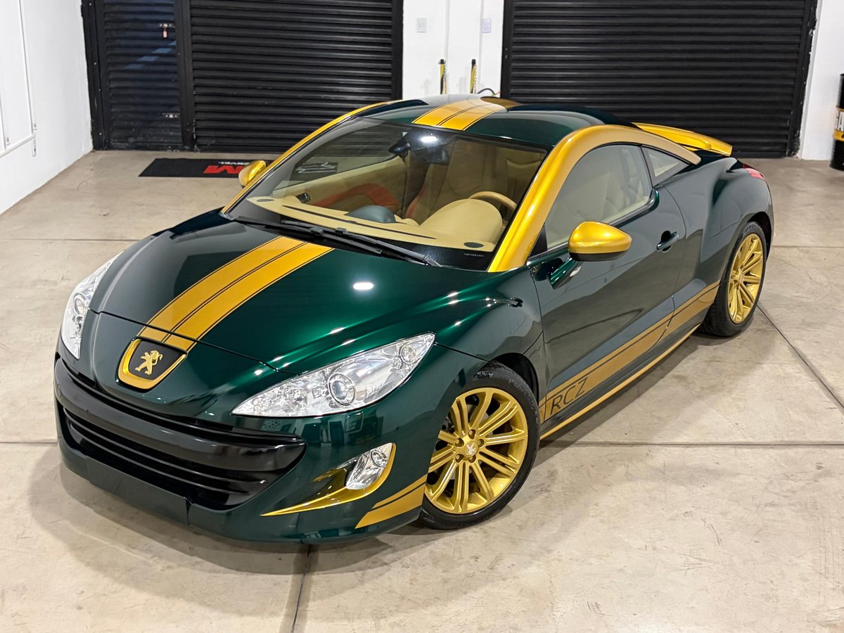 Peugeot RCZ verde com faixas douradas dentro da Garage 237